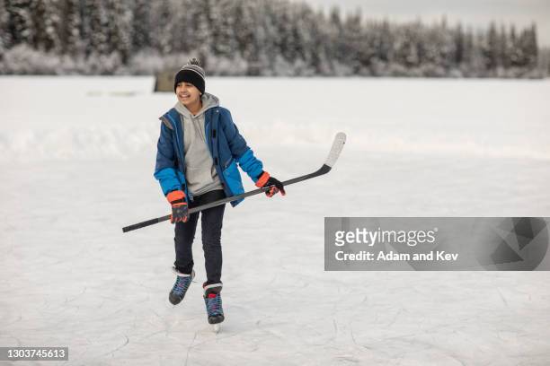 boy ice-skating with hockey stick on outdoor ice rink - hockey stick fotografías e imágenes de stock