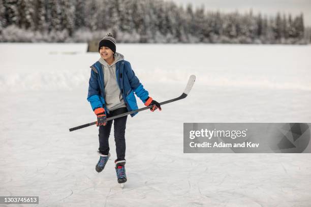 boy ice-skating with hockey stick on outdoor ice rink - ice hockey player bildbanksfoton och bilder