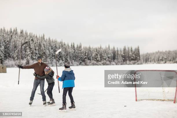 father celebrates goal with sons in ice-hockey game on outdoor ice rink - hockey rink fotografías e imágenes de stock