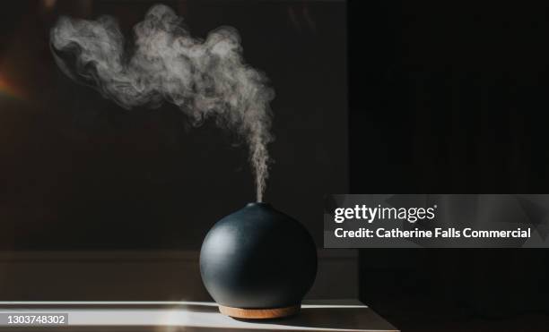 a thick mist gently rises and falls from an oil diffuser in a home environment - wispy stock pictures, royalty-free photos & images