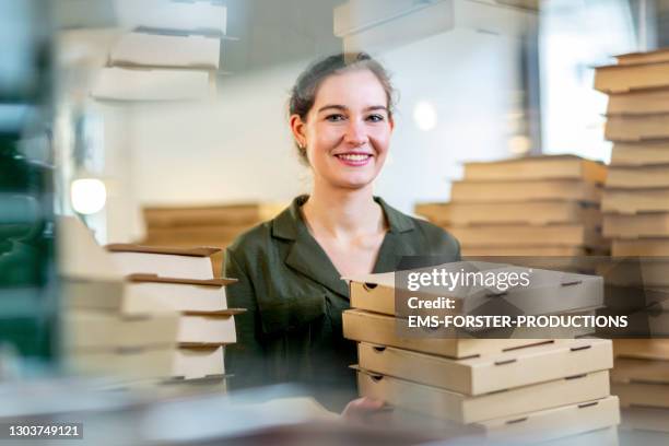 young and female small business owner with pizza boxes - blank packaging stockfoto's en -beelden