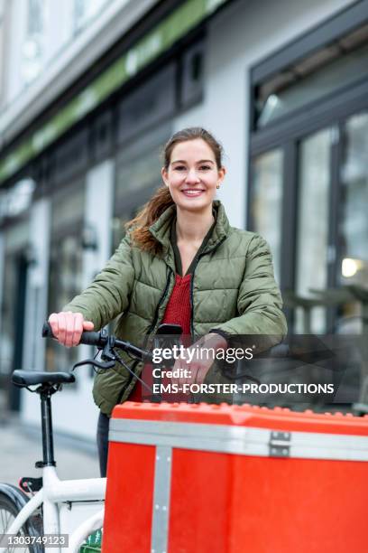 young student and delivery woman standing on her cargo bike - delivery bike stock-fotos und bilder