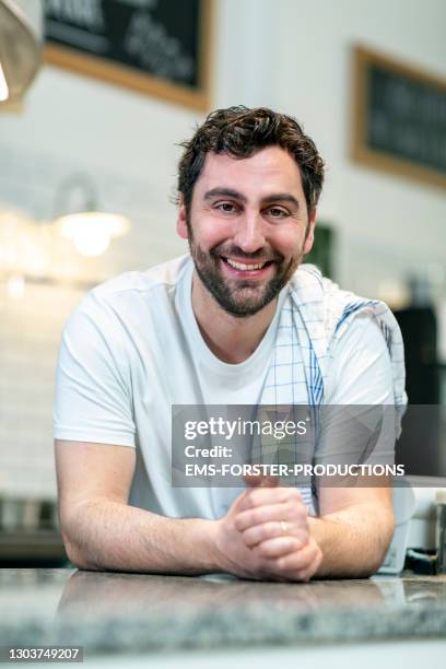 portrait of smiling pizza baker standing behind the kitchen counter - dish towel stock pictures, royalty-free photos & images