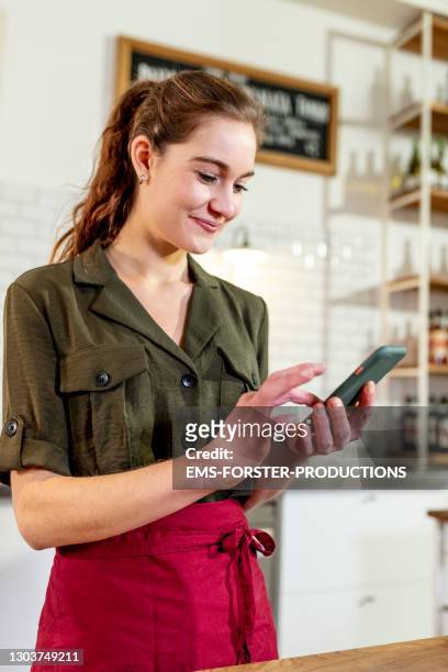young woman using mobile phone in her pizzeria - apron isolated stockfoto's en -beelden