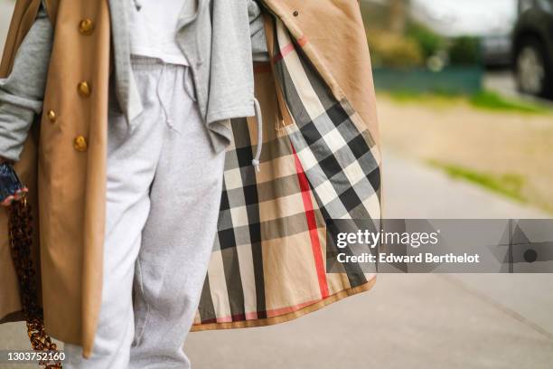 Emy Venturini wears a gray sportswear sweater from Ipsilon Paris, gray jogger pants from Adidas, a beige long trench coat with checkered inner lining...