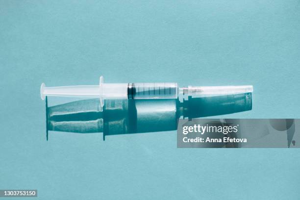 syringe on blue background with shadow - opioid epidemic stock pictures, royalty-free photos & images