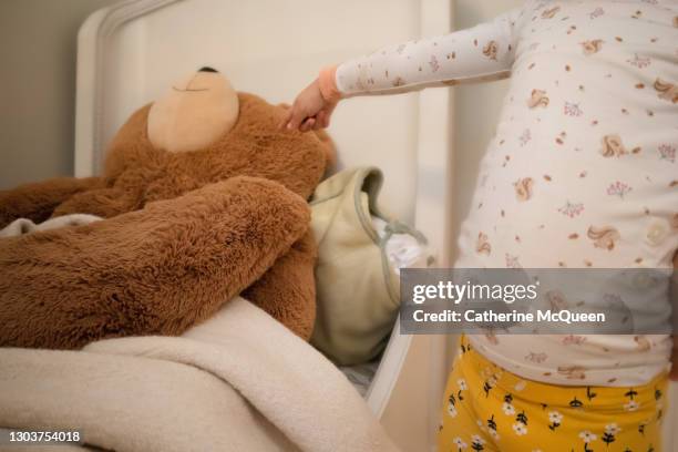 young mixed-race girl expresses surprise at finding oversized stuffed toy teddy bear in her bed - too big for bed stock pictures, royalty-free photos & images