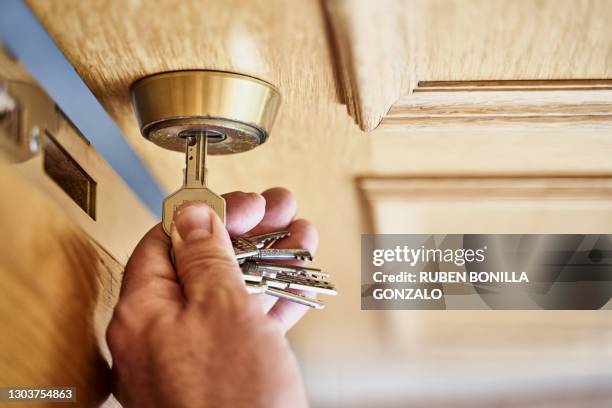 caucasian hand with key opening a wooden door - slot beveiligingsapparatuur stockfoto's en -beelden