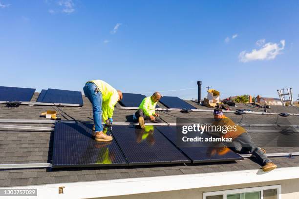 team of workers installing solar panels on residential rooftop in california - panel solar stock pictures, royalty-free photos & images