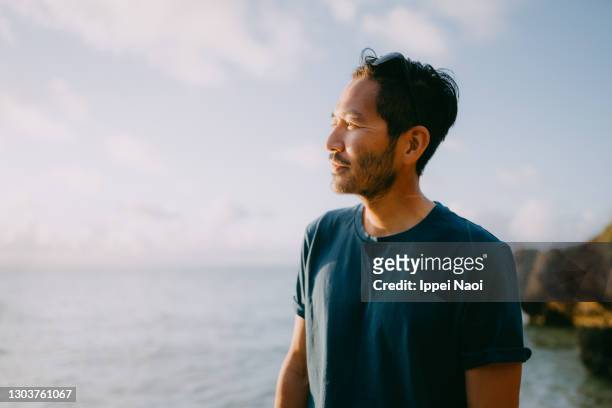 portrait of japanese man at beach - sea outdoors mature stock-fotos und bilder
