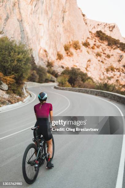 rear view of woman ready to cycling on mountain highway on road triathlon bicycle - first person perspective stock-fotos und bilder