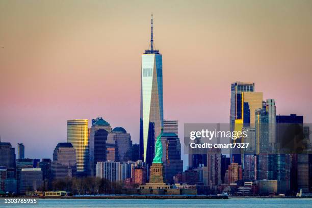 freiheitsstatue mit manhattan im hintergrund - new york freiheitsstatue stock-fotos und bilder