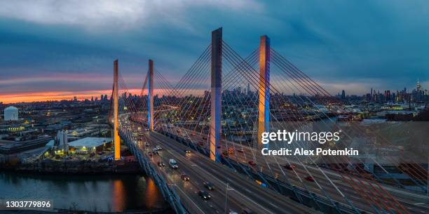 flygfoto över upplysta kosciuszko bridge i skymningen, med fjärrutsikt över manhattan och brooklyn över industriområdet williamsburg. högupplöst sydd panorama. - williamsburg new york city bildbanksfoton och bilder