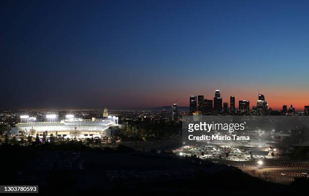 Cars are lined up at the mass COVID-19 vaccination site at Dodger Stadium , with the downtown skyline in the background, on February 23, 2021 in Los...