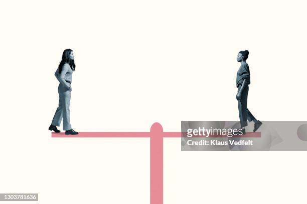 young women standing on equal-arm balance - égalité photos et images de collection