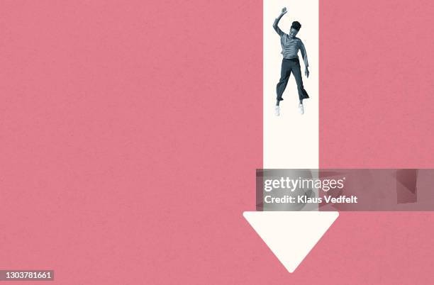 smiling young woman falling over white arrow - arrow down stock pictures, royalty-free photos & images