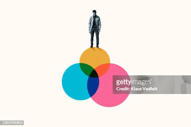 young man standing on top venn diagram of colorful circles - cmyk stock pictures, royalty-free photos & images