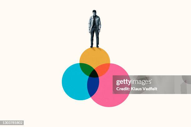 young man standing on top venn diagram of colorful circles - venn diagram imagens e fotografias de stock