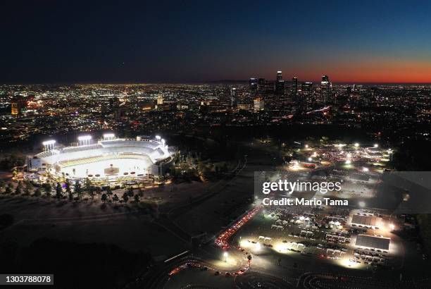 In an aerial view from a drone, cars are lined up at the mass COVID-19 vaccination site at Dodger Stadium , with the downtown skyline in the...