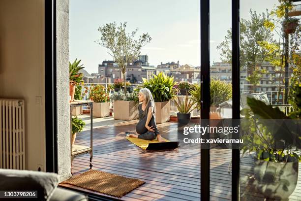 teruggetrokken hogere vrouw die yoga op zonnig openluchtdek geniet - dakterras stockfoto's en -beelden