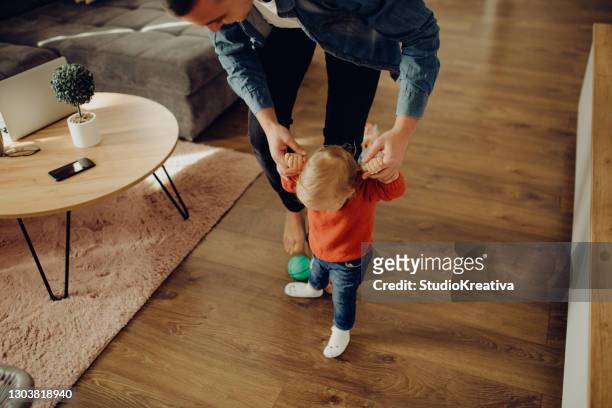 young father is playing with his baby in the living room - beautiful blonde babes stock pictures, royalty-free photos & images