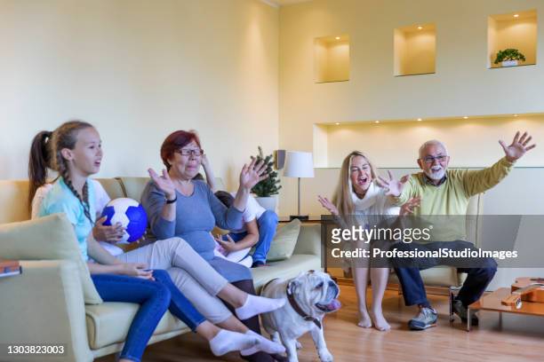 a happy family is watching a football game at home. - family tv pet stock pictures, royalty-free photos & images