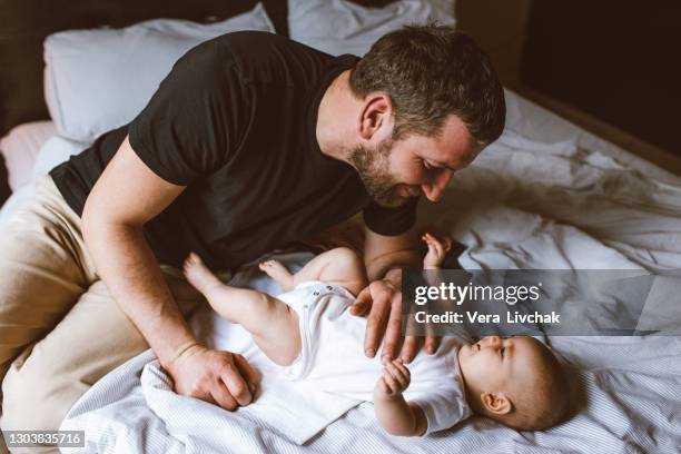 middle age caucasian father changing diaper for newborn baby daughter. male man parent taking care of child at home alone. authentic lifestyle candid moment. single dad family life concept. - changing diaper stock-fotos und bilder