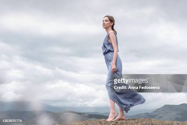 beautiful girl in a blue dress. mountain altai nature. windy weather. tourist trip. photo session in the mountains. - 自然な状態 ストックフォトと画像