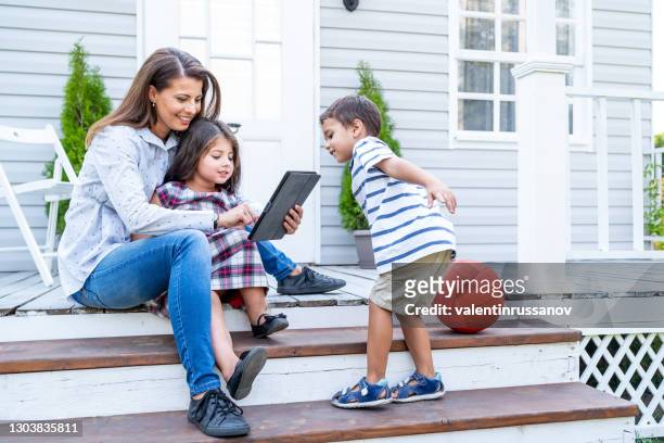 toddlers having fun in front of a house with their mother - family porch stock pictures, royalty-free photos & images