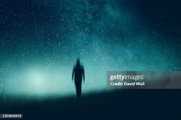 an atmospheric, moody concept of a figure walking towards the camera silhouetted against the night sky. with an abstract, artistic edit. - alienígena - fotografias e filmes do acervo