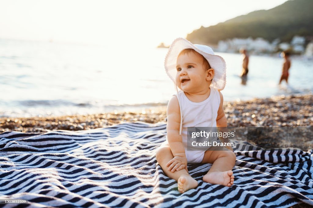 Chéri avec le chapeau se reposant sur la serviette à la plage en été