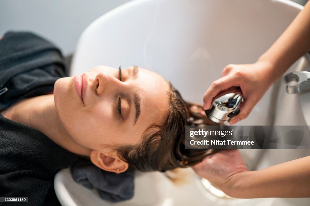 Young women customer washing her hair by beautician after dye hair at beauty salon. Beauty Salon business.