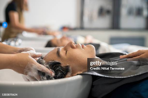 man getting hair washed by hairdresser at hair salon. hair salon beauty treatment for everyone. - shampoo stockfoto's en -beelden