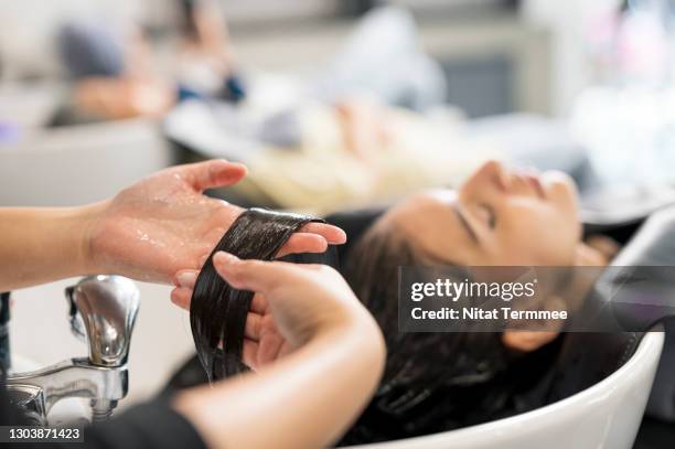 shot of relaxed customers getting a hair washed by beautician at the beauty salon. focus hand of hairstylist washed of customer hair. hair treatment, hair care. beauty hair salon business. - hairdresser foto e immagini stock