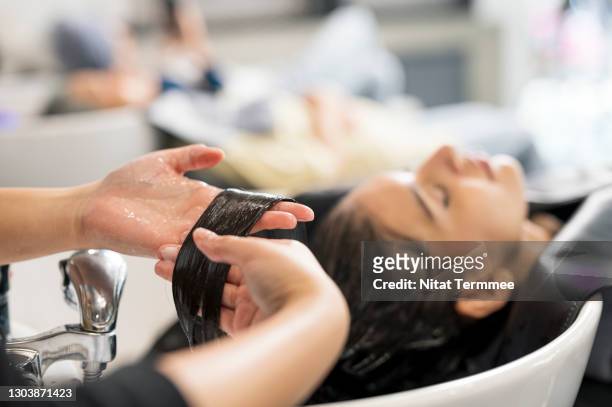 shot of relaxed customers getting a hair washed by beautician at the beauty salon. focus hand of hairstylist washed of customer hair. hair treatment, hair care. beauty hair salon business. - women washing hair stock pictures, royalty-free photos & images