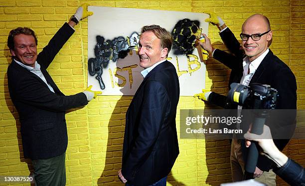 Hans Joachim Watzke, CEO of Borussia Dortmund, sprays on a wall between Matthias Baeumer, director Puma Germany, and Franz Koch, CEO of Puma, during...