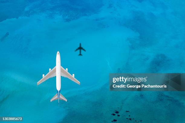 top down aerial photo of a passenger plane flying above the blue sea - plane in sky stock-fotos und bilder