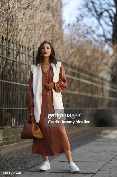 Masha Sedgwick wearing Envelope 1976 brown dress, Polene beige bag, Zara beige vest, Copenhagen Studios white sneaker on February 22, 2021 in Berlin,...