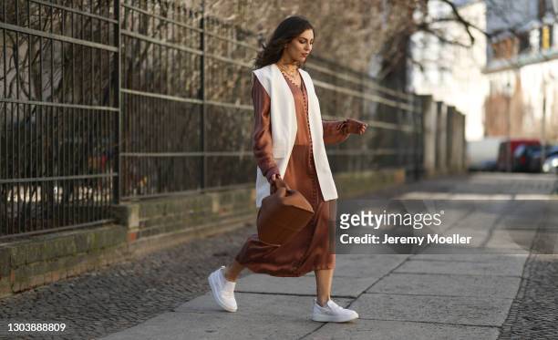 Masha Sedgwick wearing Envelope 1976 brown dress, Polene beige bag, Zara beige vest, Copenhagen Studios white sneaker on February 22, 2021 in Berlin,...