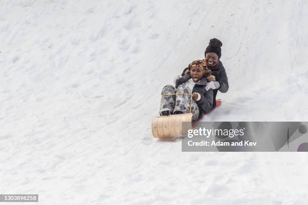 mother and daughter ride wooden sled down snowy hill - treno - fotografias e filmes do acervo