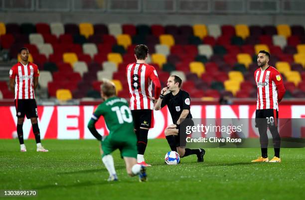 Match Referee, Jeremy Simpson takes a knee in support of the Black Lives Matter movement as Saman Ghoddos of Brentford stands with team mates prior...