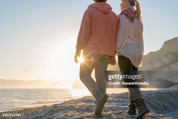 couple walk along beach, at sunrise - early retirement stock pictures, royalty-free photos & images