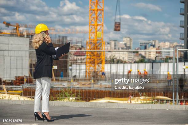 mulher gerente de construção usando celular enquanto verifica obras no canteiro de obras - mobile crane - fotografias e filmes do acervo