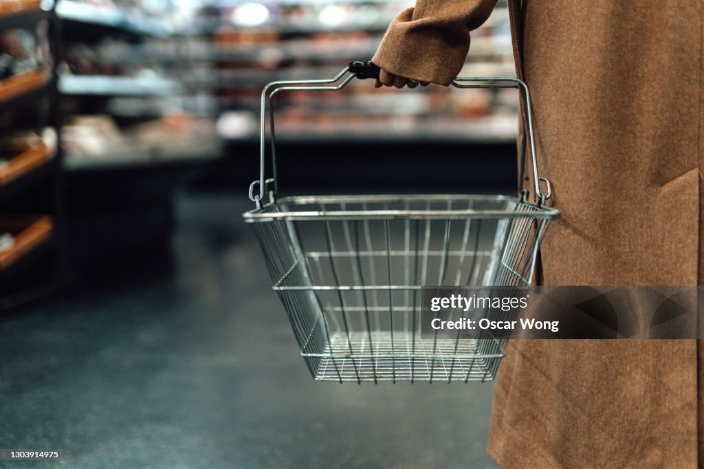 Woman carrying empty shopping basket in supermarket