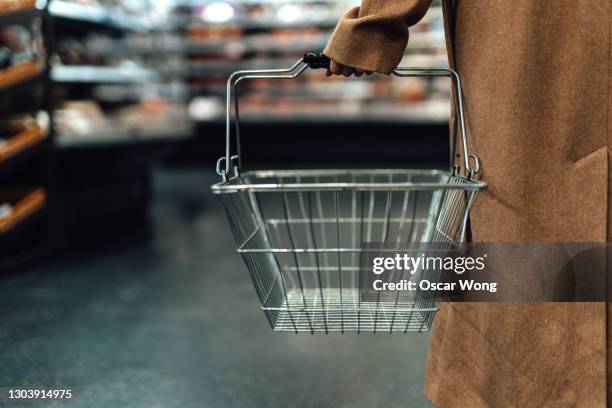 woman carrying empty shopping basket in supermarket - cesto de compras imagens e fotografias de stock