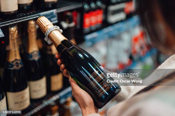 woman choosing champagne in liquor store - bottle shop stock-fotos und bilder