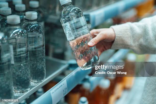 woman buying bottled water in convenience store - bottiglie foto e immagini stock