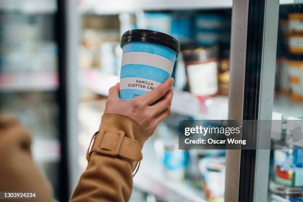close up shot of woman holding a cup of vanilla flavour ice cream in supermarket. - refrigerated section supermarket stock pictures, royalty-free photos & images