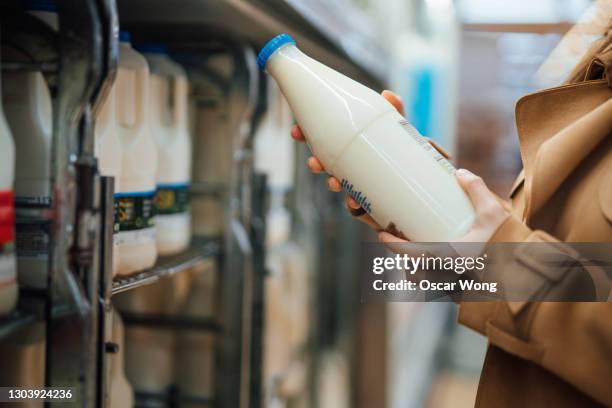 close up shot of woman holding a bottle of organic fresh milk in supermarket - dairy product stock-fotos und bilder