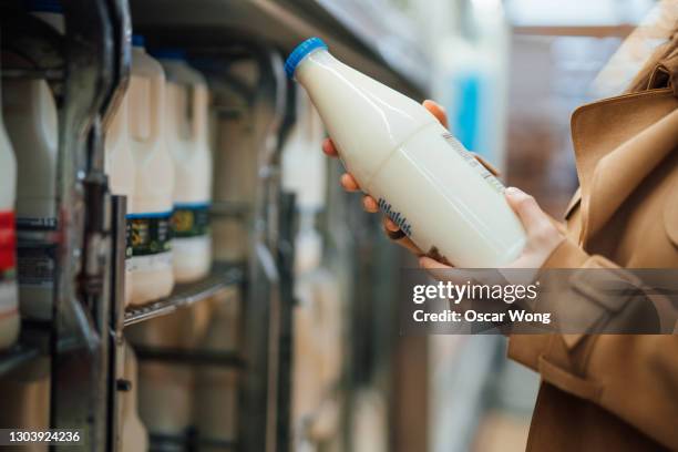 close up shot of woman holding a bottle of organic fresh milk in supermarket - soya milk stock pictures, royalty-free photos & images